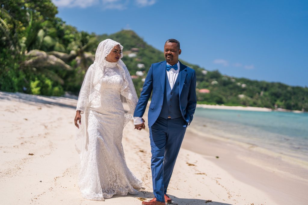 Bride and groom walking on Seychelles beach after their wedding ceremony
